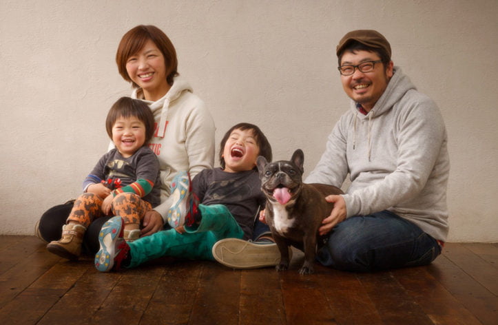 舌を出している犬と笑顔の4人家族